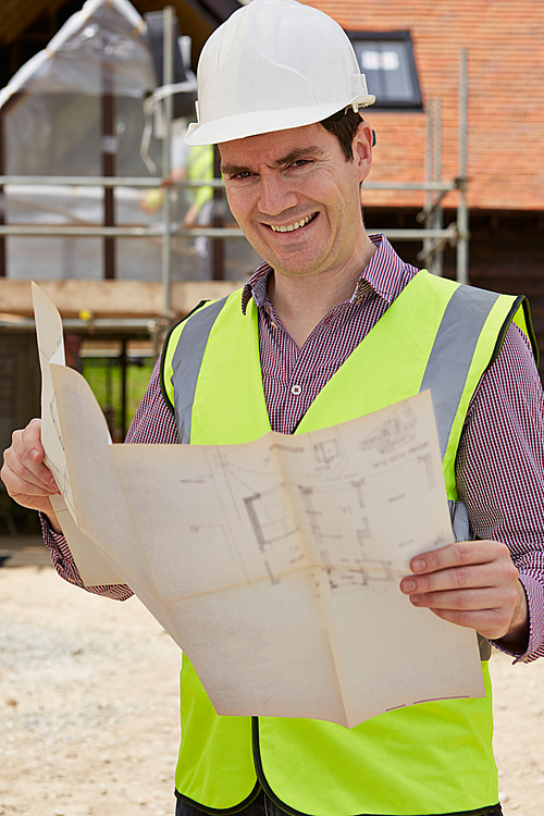 Portrait Of Architect On Building Site Looking At House Plans