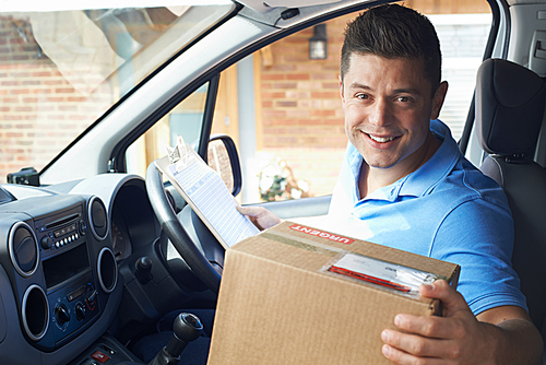 Portrait Of Courier In Van Delivering Package To  House