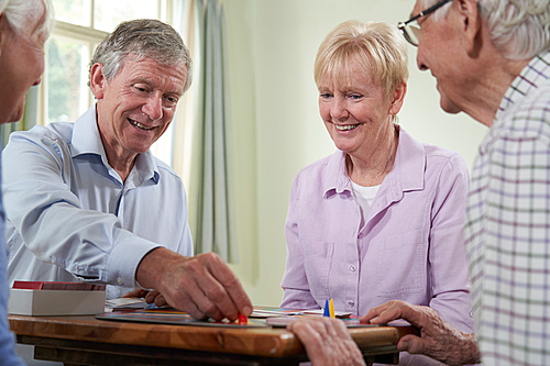 Group Of Retired Friends Playing Board Game At Social Club