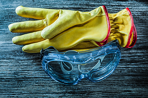 Protective leather gloves glasses on wooden board.