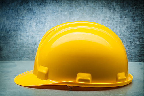 yellow  construction helmet on metalic background close up side view