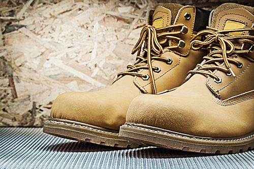 brown working boots on plywood background