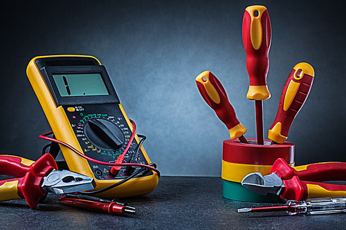 multy colored electrical tools on gradient gray background