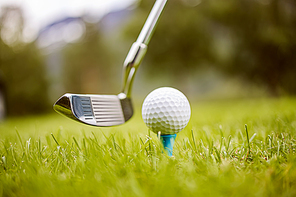 Golf club and ball on tee in front of driver