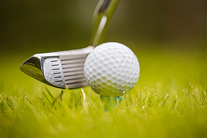 Golf club and ball on tee in front of driver