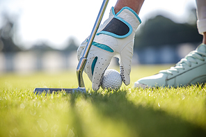 Hand in glove placing golf ball on tee