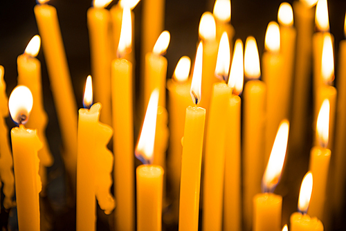 Many burning yellow wax candles in church. Venice, Italy