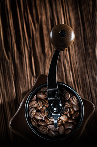 Coffee mill natural beans on vintage wooden board.