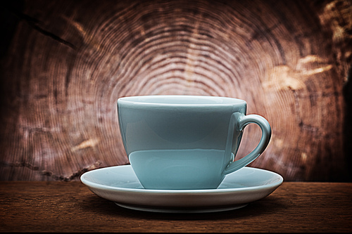 big white coffee cup for capuchino on vintage wood background with cross cut of tree trunk