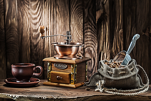 coffee accessories brown clay cup vintage wooden mill and sack with beans scoop on old wood background