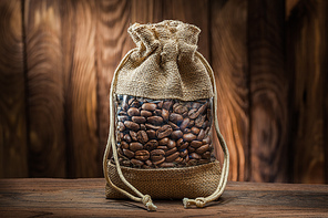 vintage burlap bag with coffee beans on old wooden background