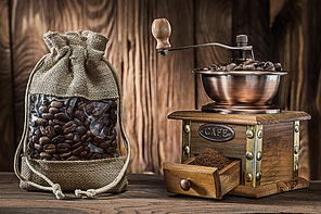 vintage sack with coffee beans and wooden mill on wood background