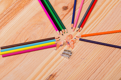 Wooden colorful pencils with sharpening shavings, on wooden table