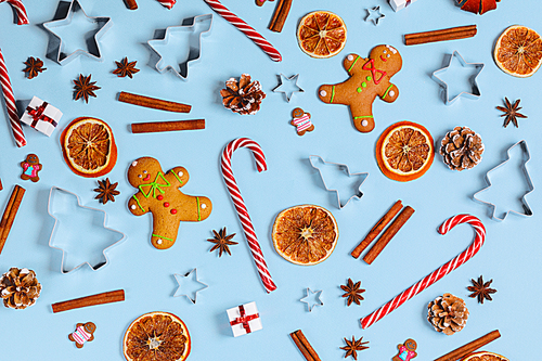 Christmas food gingerbread cookie caramel candy cane cinnamon mold shape anise orange slice and gifts on blue background