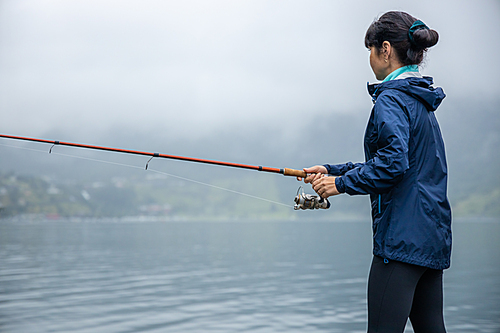 Woman fishing on Fishing rod spinning in Norway. Fishing in Norway is a way to embrace the local lifestyle. Countless lakes and rivers and an extensive coastline means outstanding opportunities...