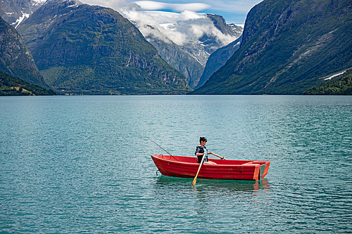 Woman fishing on a boat. Beautiful Nature Norway natural landscape. lovatnet lake Lodal valley.