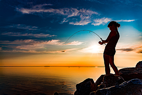 Woman fishing on Fishing rod spinning in Norway. Fishing in Norway is a way to embrace the local lifestyle. Countless lakes and rivers and an extensive coastline means outstanding opportunities...