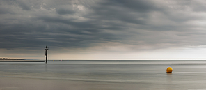 Beautiful panorama landscape image of beach at low tide with moody storm clouds gathering overhead