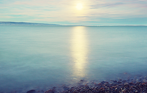 Full moon rising above mountain lake