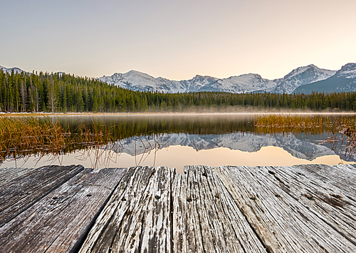 Bierstadt Lake and reflection with mountains in snow around at autumn. Fog on the water. Rocky Mountain National Park in Colorado, USA.