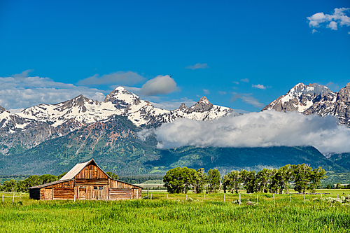 Old mormon barn in Grand Teton Mountains with low clouds. Grand Teton National Park, Wyoming, USA.