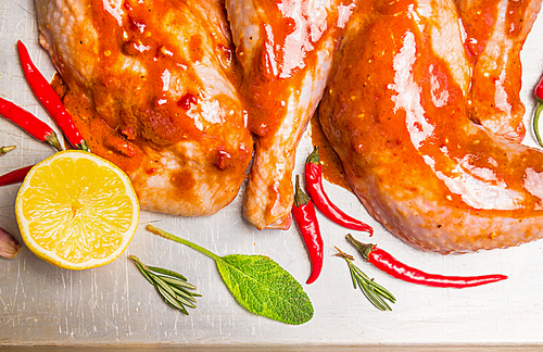 chicken legs with red chili sauce and lemon, top view, close up