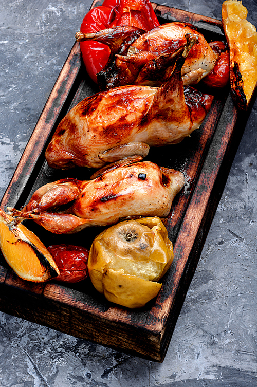 Quail fried with orange and apples.Roasted quail on cutting board