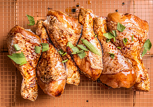 Close up of Raw marinated chicken drumsticks on grill grid with ingredients,  herbs and spices, top view