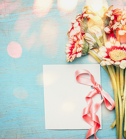 Beautiful flowers bunch with empty greeting card ,ribbon and bokeh on blue  shabby chic background, top view