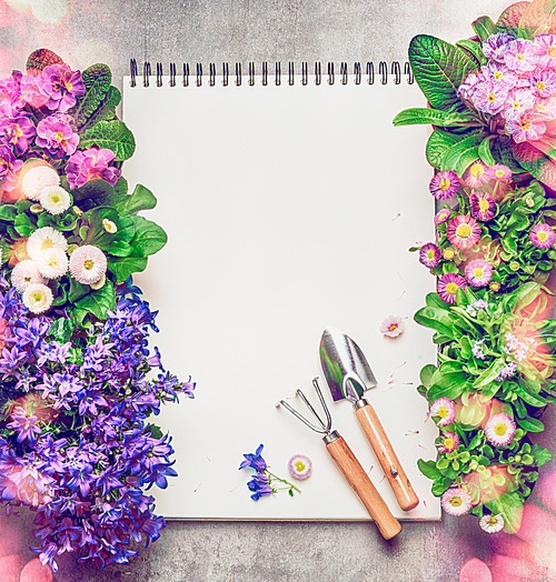 Floral Gardening background with assortment of colorful garden flowers in pots , blank paper notebook and gardening tools, top view, frame