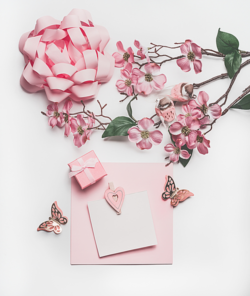 Pretty pastel pink greeting card mock up with blossom decoration, hearts, little gift box and bow on white desk background, top view, flat lay. Wedding invitation  layout or Mother Day  concept