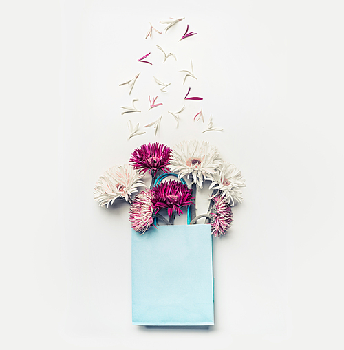 Fresh lovely flowers in blue paper shopping bag on white desktop background, Top view , copy space