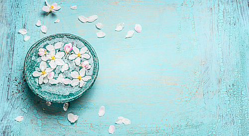 Beautiful spring blossom with white flowers in water bowl on Turquoise blue shabby chic wooden background, top view. Wellness and spa concept. Spring blossom background, banner