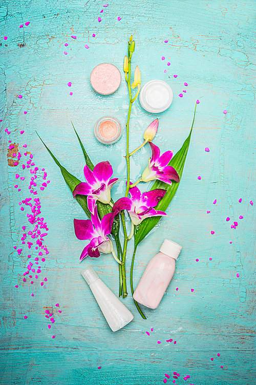 Spa or wellness composing with pink orchid , cream and lotion on turquoise blue shabby chic background, top view