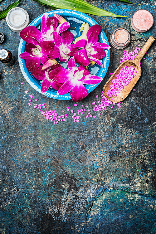 wellness or spa background with pink orchid flowers  in bowl with water, shovel of 씨솔트, cream jar , candles and green bamboo leaf . top view, place for text.