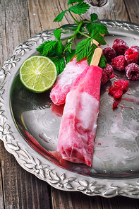 two popsicles served with raspberries and lime on a metal tray.Selective focus