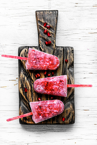 three pomegranate ice creams on sticks on the kitchen board