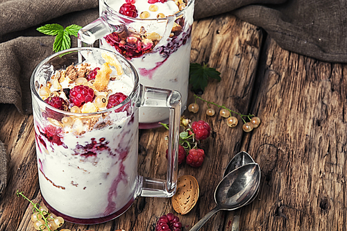 Raspberry ice cream with almonds and currants in glass cup.Sundae on a vintage rustic background.