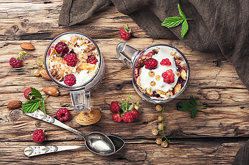 Raspberry ice cream with almonds and currants in glass cup.Sundae on a vintage rustic background.