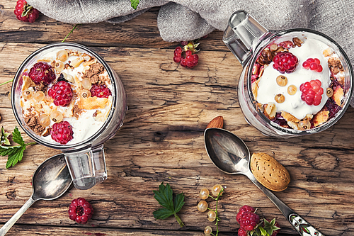 Raspberry ice cream with almonds and currants in glass cup.Sundae on a vintage rustic background.