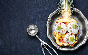 Ice cream in pineapple bowl, decorated with kiwi and pomegranate