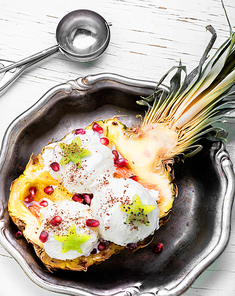 Ice cream in pineapple bowl, decorated with kiwi and pomegranate.Icecream dessert