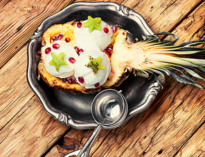 Ice cream in pineapple bowl, decorated with kiwi and pomegranate.Icecream dessert