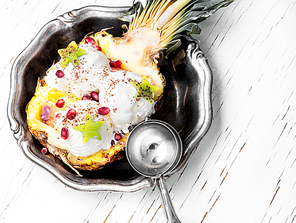 Ice cream in pineapple bowl, decorated with kiwi and pomegranate.Icecream dessert