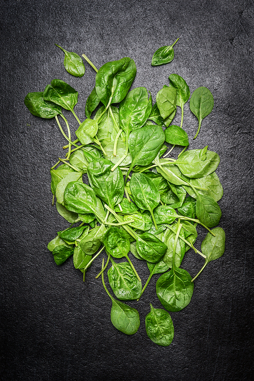 Fresh spinach leaves on dark wooden background, top view