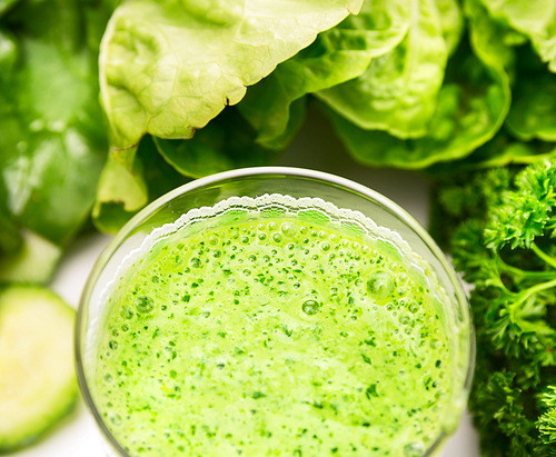 green smoothie over vegetables background, close up