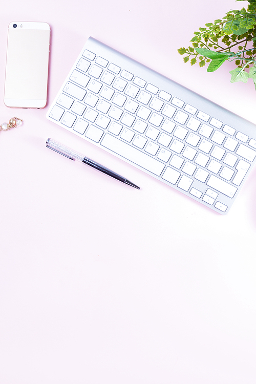 Flat lay home office workspace - white modern keyboard on pink background