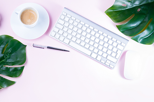 Flat lay home office workspace - white modern keyboard with coffee cup on pink background