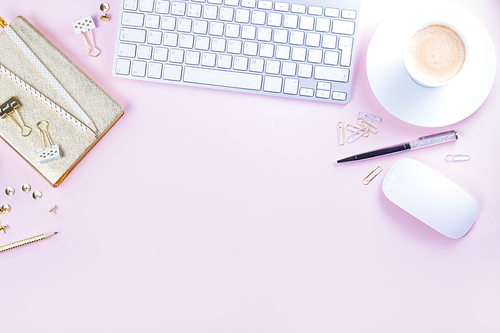 Flat lay home office workspace - white modern keyboard on pink background with copy space