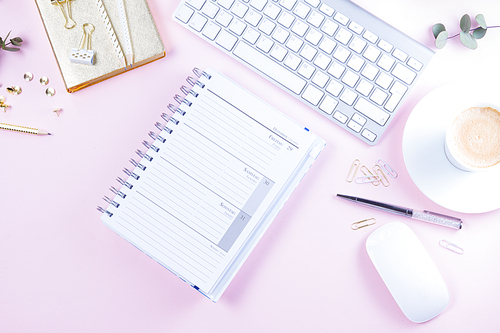 Flat lay home office workspace - white modern keyboard with notebook on pink background